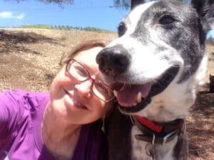 Black and white saluki-cross rescue dog sitting with female owner, heads close together